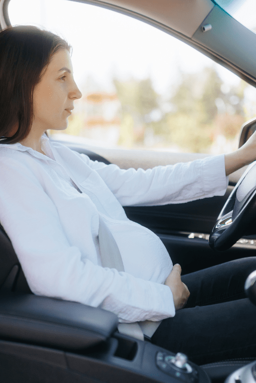 young pregnant woman driving a car on a sunny day